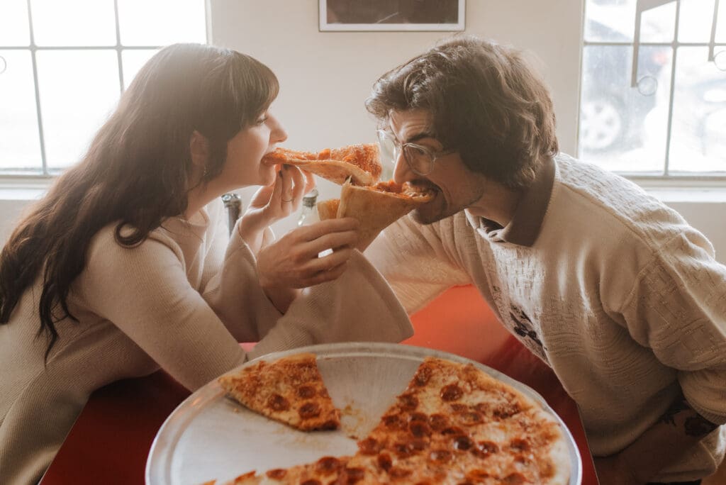 A couple eats pizza at Winnipeg's local pizzeria, Shorty's pizza, during their engagement session.