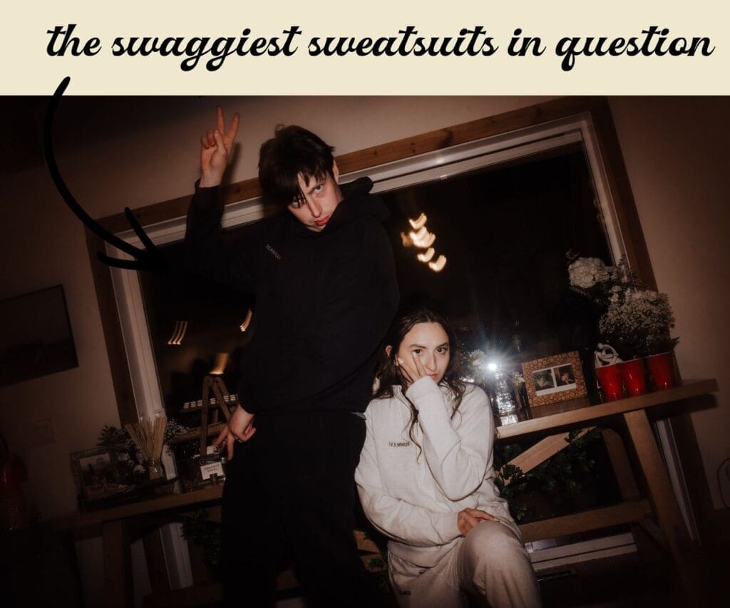 An image featuring the bride and groom's wedding tracksuits. They are posing in the cabin at Falcon Trails Resort acting as their reception site. The photo is taken with flash to emulate film.